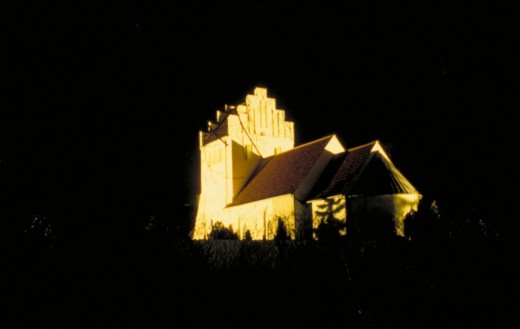 Belyst landsbykirke. Læg mærke til, hvordan især tårnet har fået et skråt snit af lyset. Fot.: P.T.Aldrich.